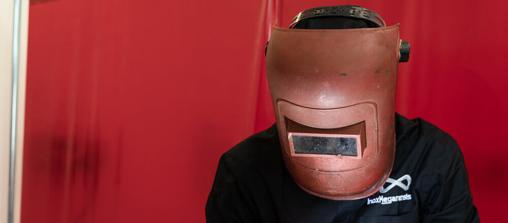 saldatore effettua una saldatura indossando un casco rosso